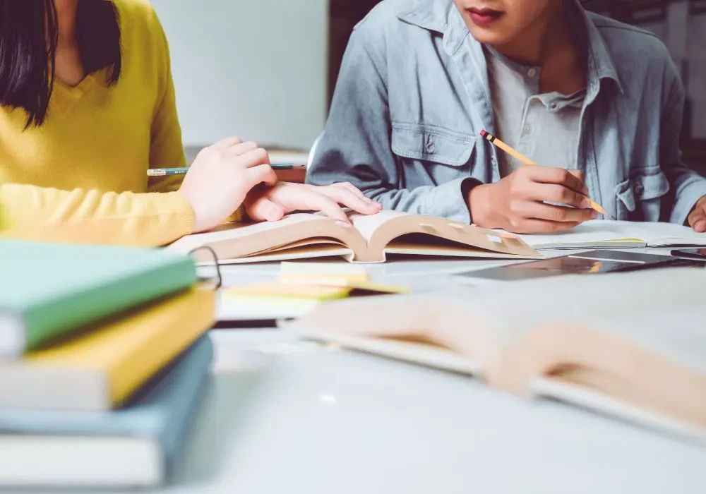 Two students poring over a book quietly in class