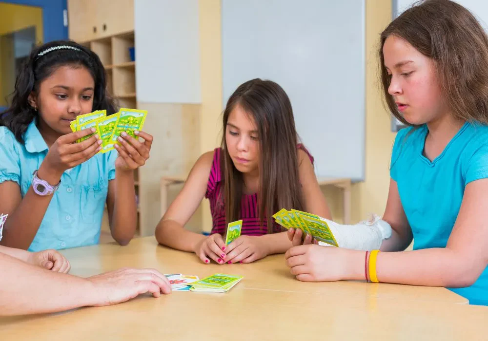 Three female students playing card games in a classroom